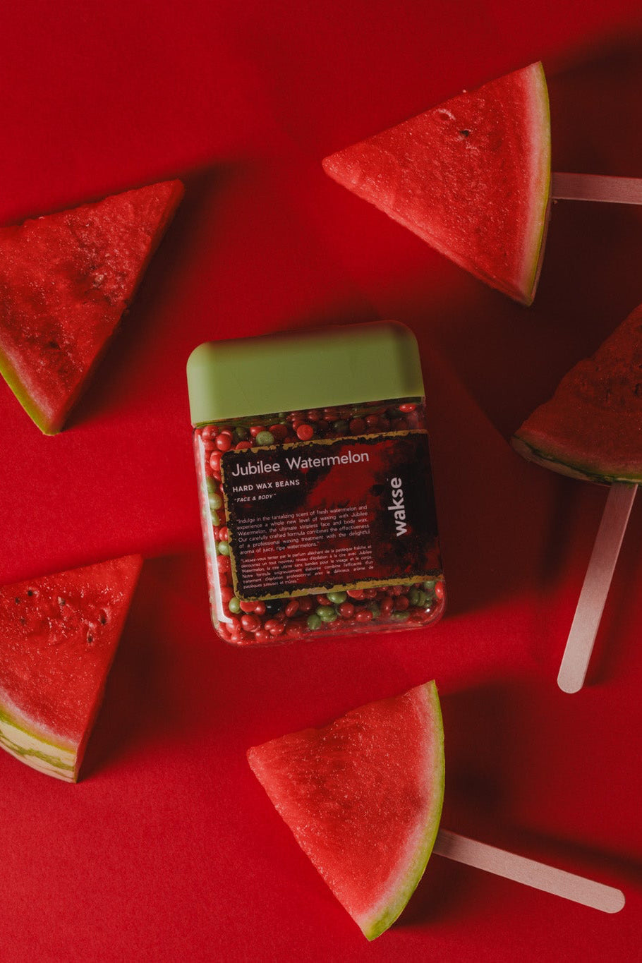 wakse Watermelon slices on sticks with a container of watermelon-flavored jelly on a red background